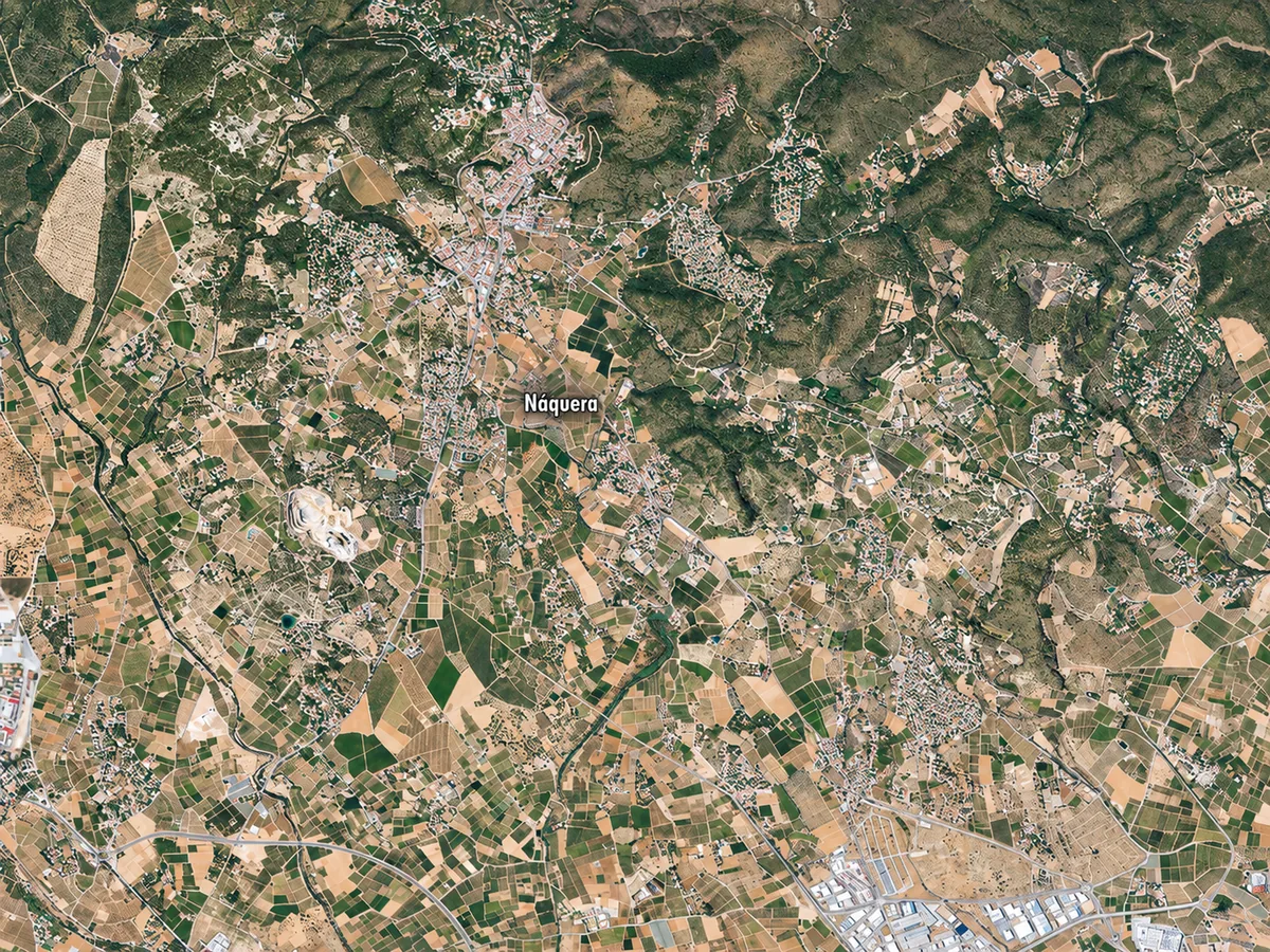 Vista aérea de zonas arboladas, campos, áreas residenciales, naves y carreteras, con el rótulo Náquera